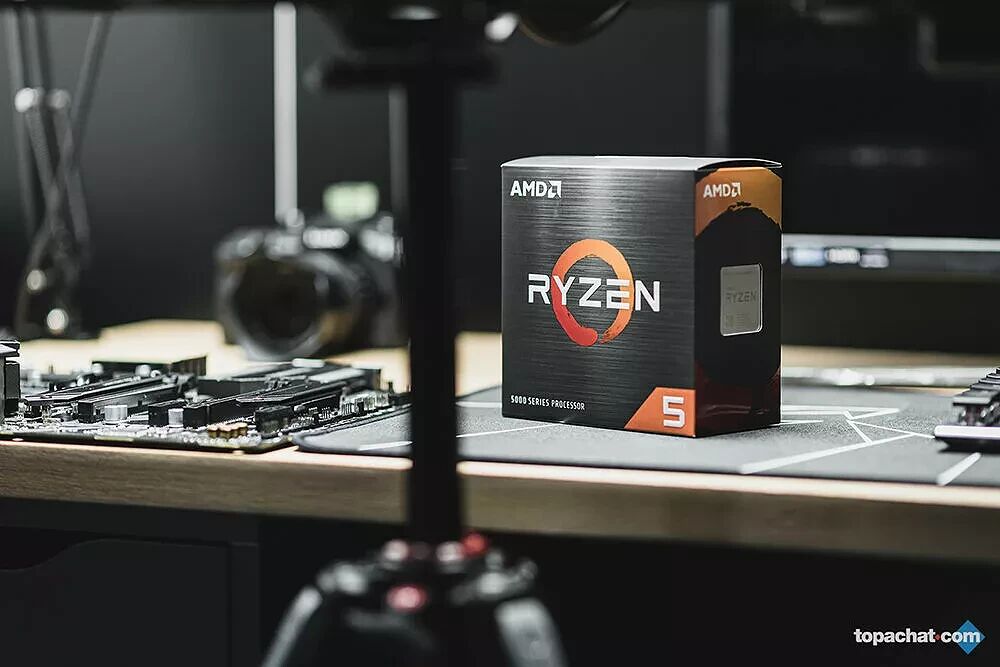 Boîte d'un processeur AMD Ryzen série 5000 posée sur un bureau à côté d'une carte mère.