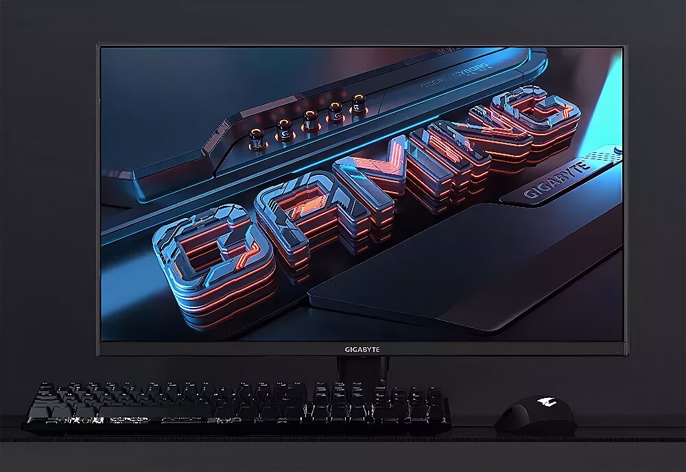 Un écran de PC Gigabyte affichant un fond d'écran stylisé avec le mot "DIVINE", accompagné d'un clavier et d'une souris gamer noirs sur un bureau.