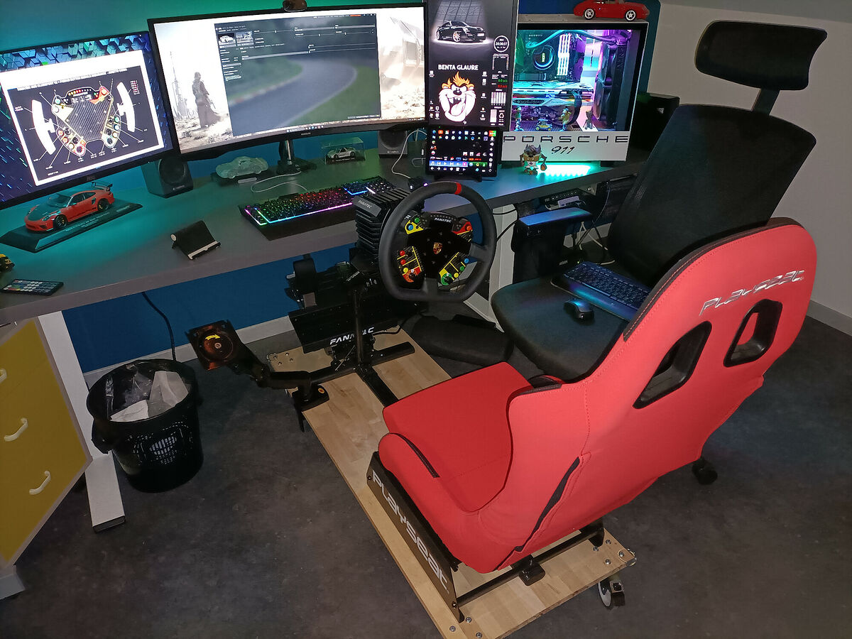 Setup de Bentaglaure : baquet de simulation rouge sur châssis, volant à retour de force Fanatec et levier de vitesse, à côté d’un bureau gaming en triple écran