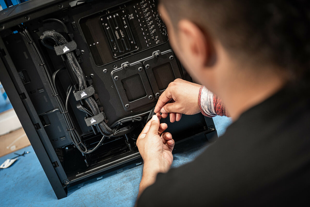 Technicien vu de dos en train d'assembler un PC en atelier