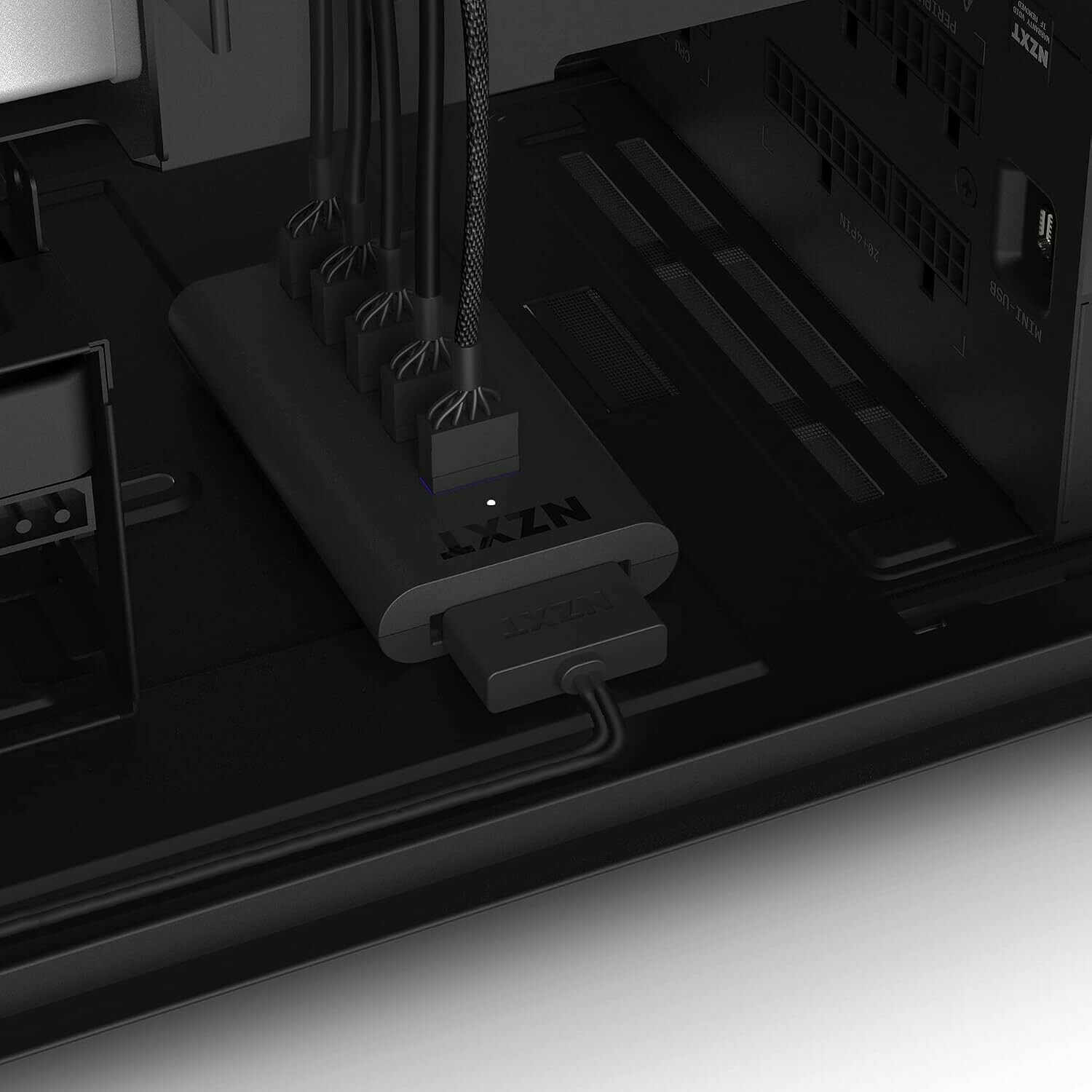 Un hub de gestion de câbles NZXT noir installé à l'intérieur d'un boîtier PC, avec plusieurs câbles reliés à ses ports.