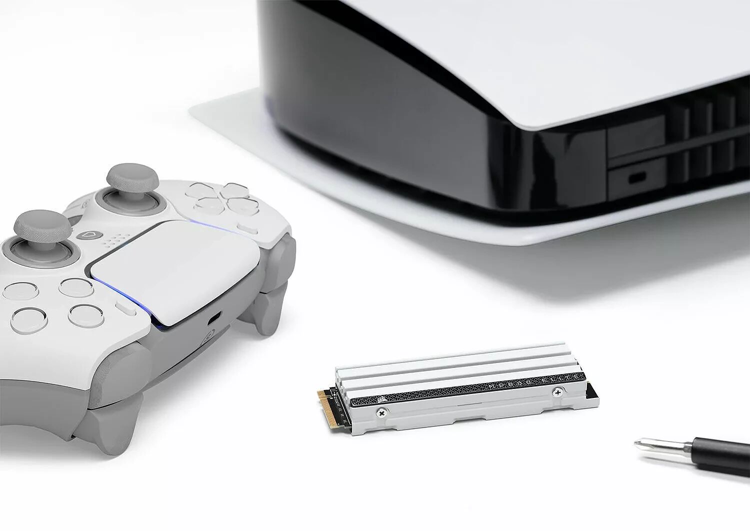 Une manette blanche et grise posée à côté d'une console de jeux et d'un SSD interne de type M.2.