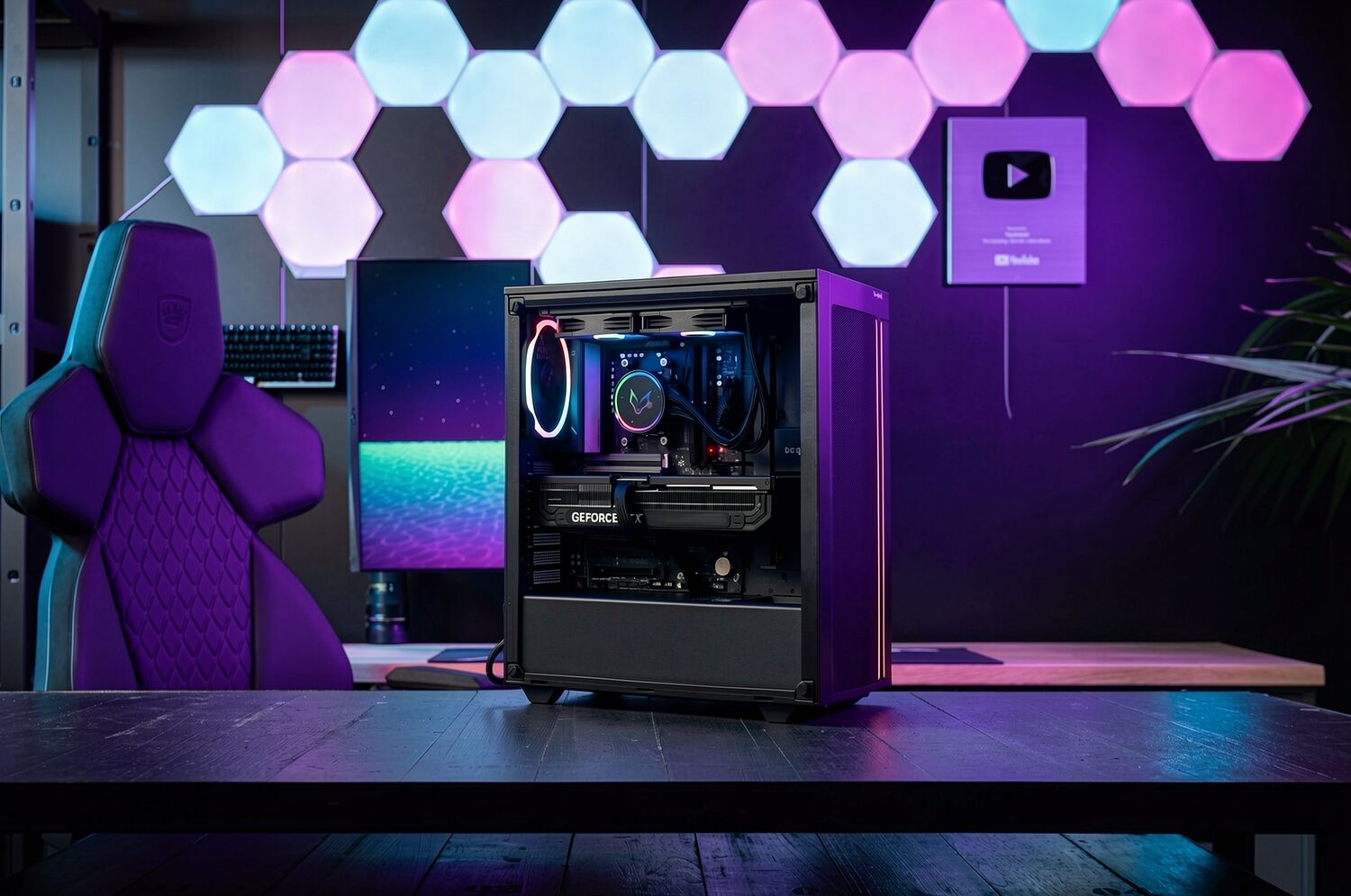 Un PC gamer avec un boîtier noir vitré, éclairé par des LED violettes, posé sur un bureau devant un écran et une chaise gaming violette. Le setup est décoré de panneaux lumineux hexagonaux sur le mur.