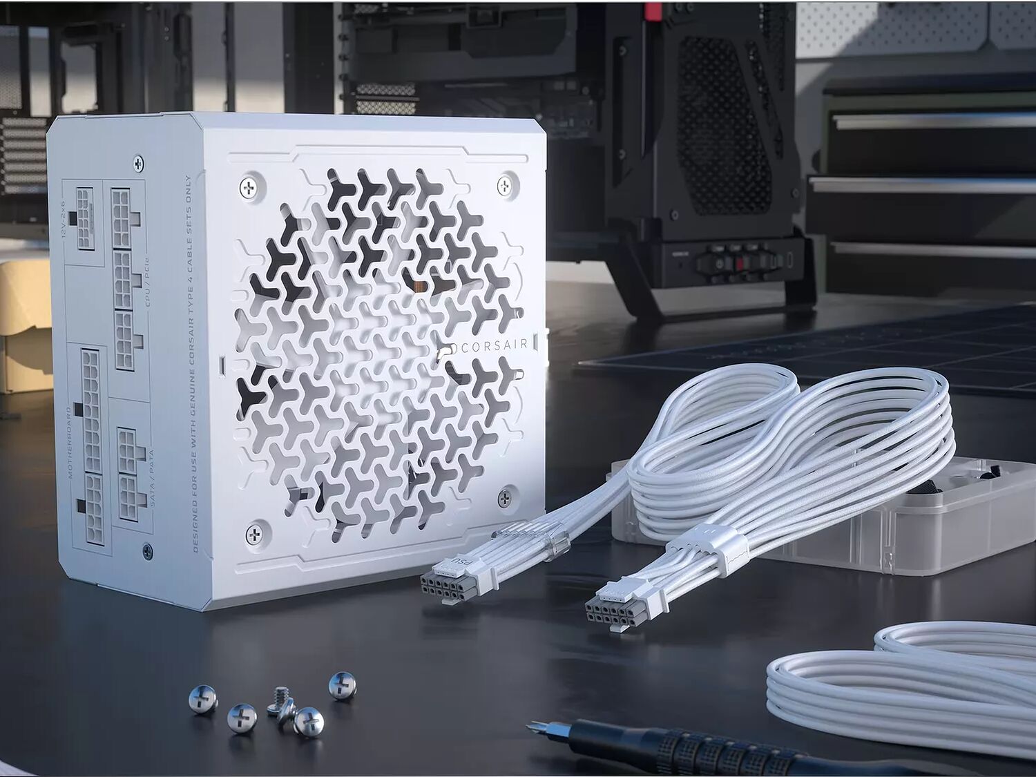Bloc d'alimentation Corsair blanc avec ses câbles modulaires assortis posés sur un bureau de montage.