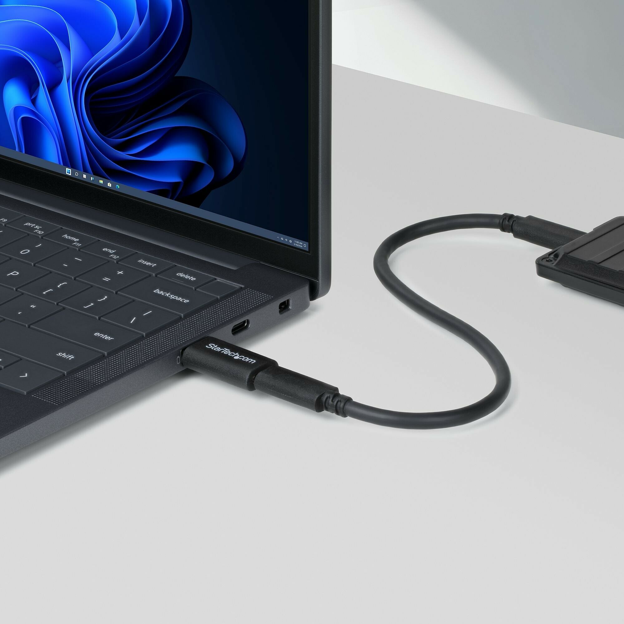 Un disque dur externe StarTech connecté à un ordinateur portable via un câble USB noir.
