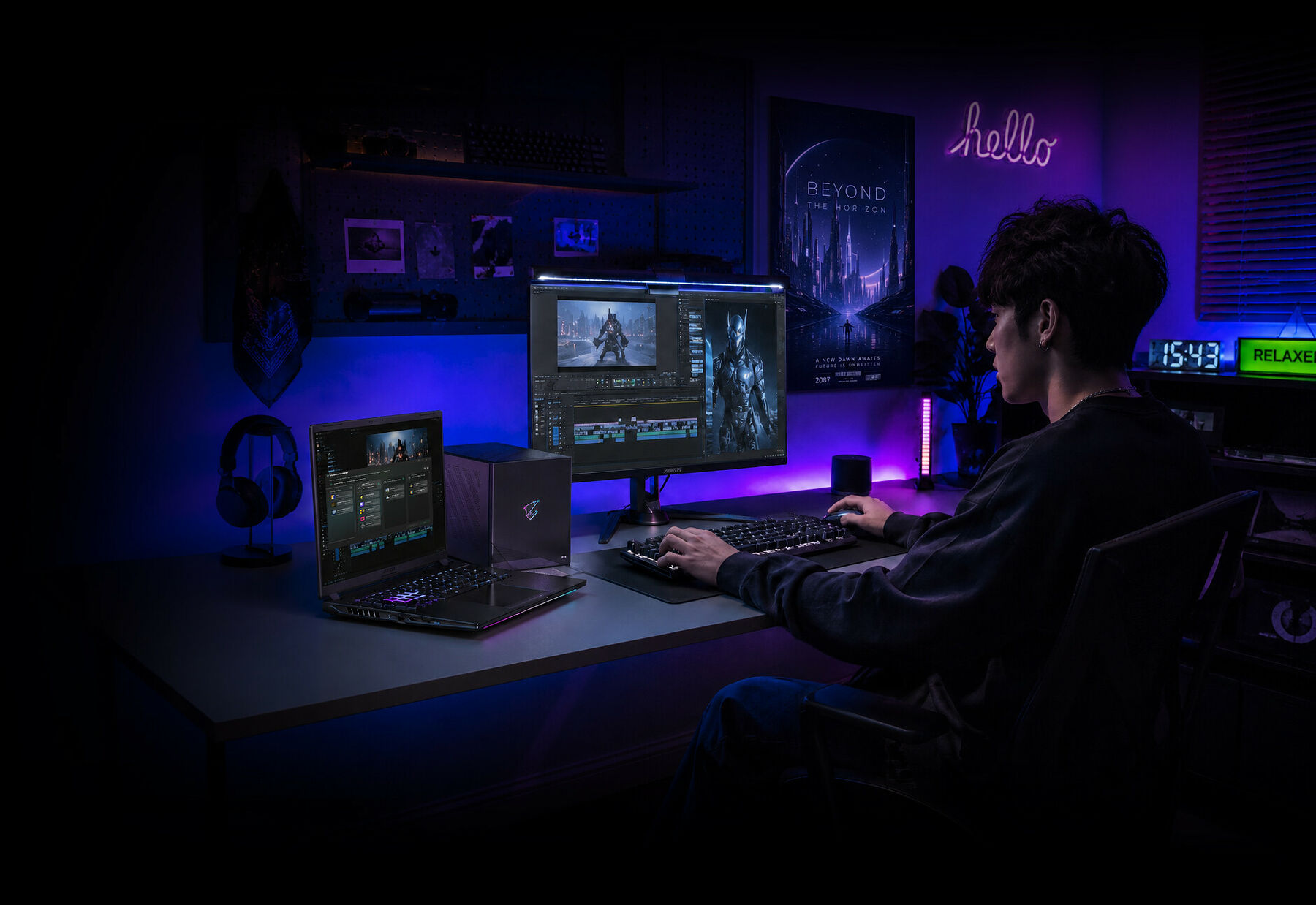 Un jeune homme utilise un PC avec deux écrans, un clavier et une souris, le tout dans une chambre éclairée par des néons violets et bleus.