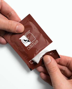 Une main ouvre un sachet de lingettes de nettoyage de la marque Noctua.