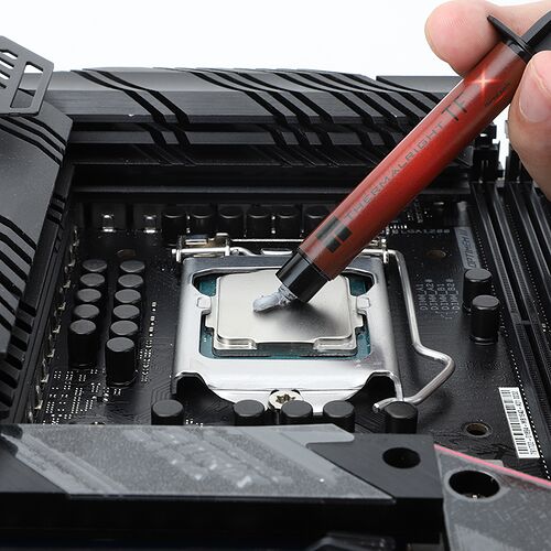 Une main applique de la pâte thermique Thermalright sur le processeur installé sur une carte mère.