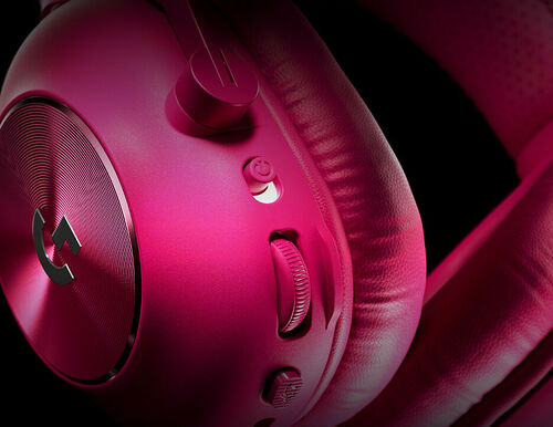 Casque audio rose avec logo circulaire sur l'écouteur et boutons de contrôle sur le côté.