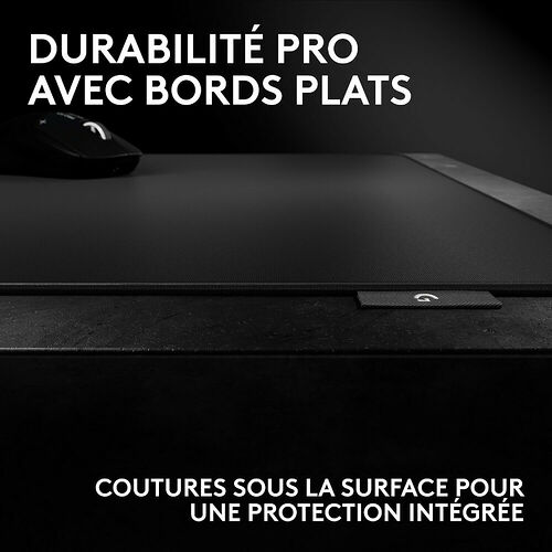 Gros plan sur un tapis de souris noir avec des bords plats et des coutures de protection sous la surface. On aperçoit également une souris noire sur le dessus.
