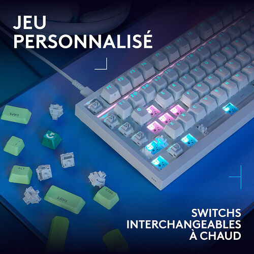 Clavier mécanique compact blanc avec touches rétroéclairées et switches interchangeables à chaud, accompagné de quelques touches de rechange de couleur verte.