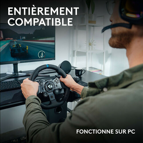 Un homme utilise un volant de simulation de course avec un casque audio devant un écran affichant un jeu de course sur un bureau.
