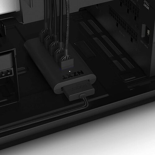 Un hub de gestion de câbles NZXT noir installé à l'intérieur d'un boîtier PC, avec plusieurs câbles reliés à ses ports.