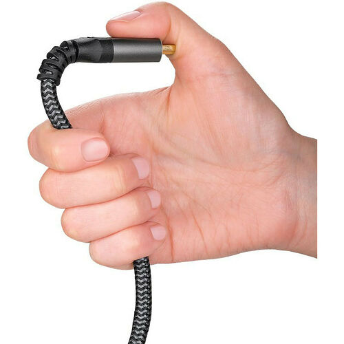 Une main tient un câble audio avec un connecteur jack doré et un revêtement en tissu tressé noir.
