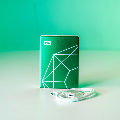 Disque dur externe WD de couleur verte avec un motif géométrique blanc et son câble USB blanc.