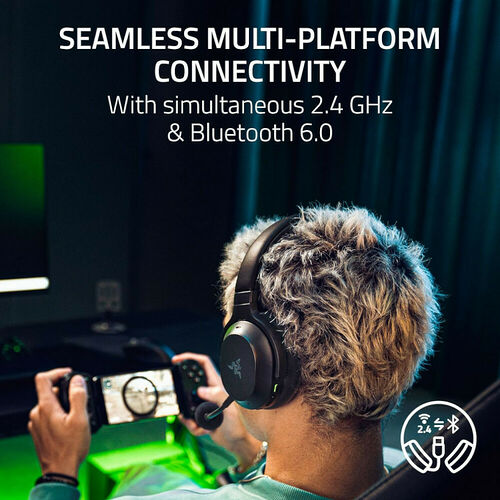 Un homme joue sur une console portable avec un casque Razer noir. Le casque dispose d'une connectivité sans fil 2.4 GHz et Bluetooth.