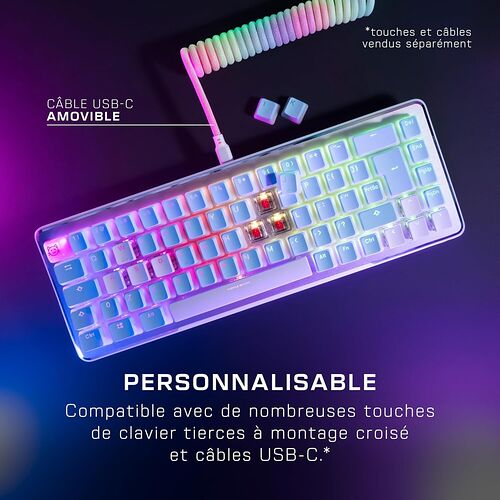 Clavier mécanique rétroéclairé avec touches blanches et châssis transparent, accompagné d'un câble USB-C amovible multicolore. Le clavier est présenté avec quelques touches détachées sur un fond violet et bleu.