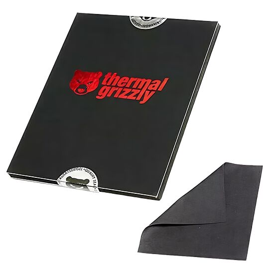 Pâte thermique Thermal Grizzly présentée dans son emballage noir avec un morceau de la matière grise visible à côté.
