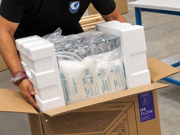 Mise en carton d’un PC monté, enveloppé dans une housse et maintenu par des cales de protection