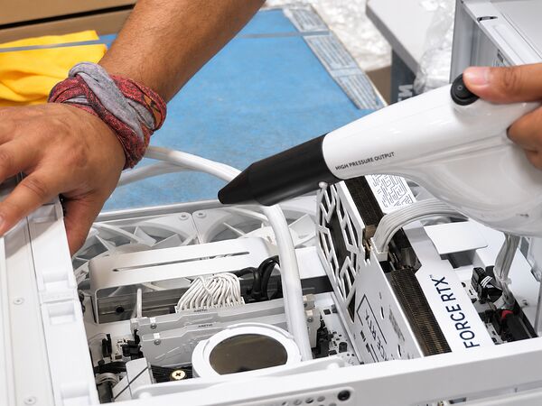 Technicien TopAchat nettoyant l’intérieur d’un PC monté avec un souffleur avant son emballage
