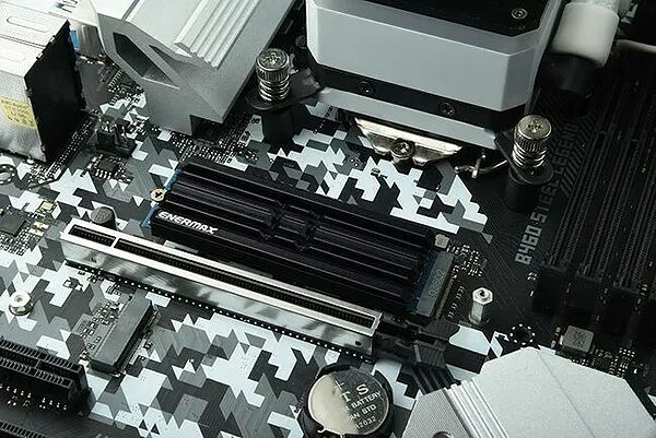 Gros plan sur une carte mère avec un motif camouflage noir et blanc, présentant des slots de mémoire RAM Enermax et divers composants électroniques.