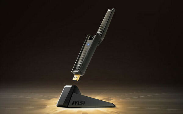 Un adaptateur sans fil MSI noir présenté sur son socle de recharge, avec un petit voyant lumineux bleu.