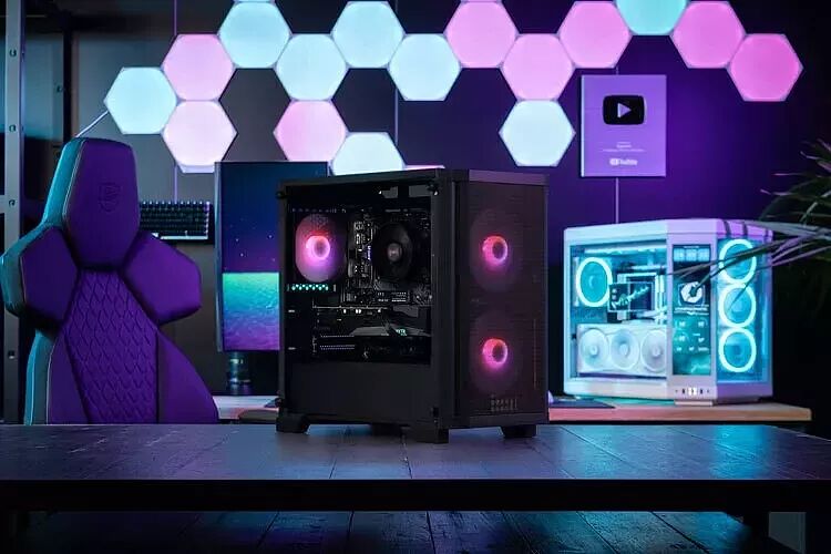Un PC avec un boîtier noir doté de ventilateurs rétroéclairés en rose, posé sur un bureau devant un mur décoré de panneaux lumineux hexagonaux.
