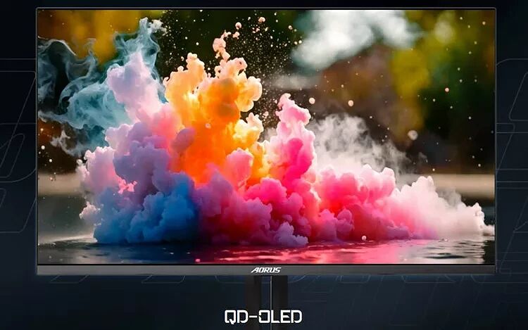 Écran de PC Aorus affichant une explosion de fumée colorée sur un fond sombre, avec la mention QD-OLED en bas de l'image.