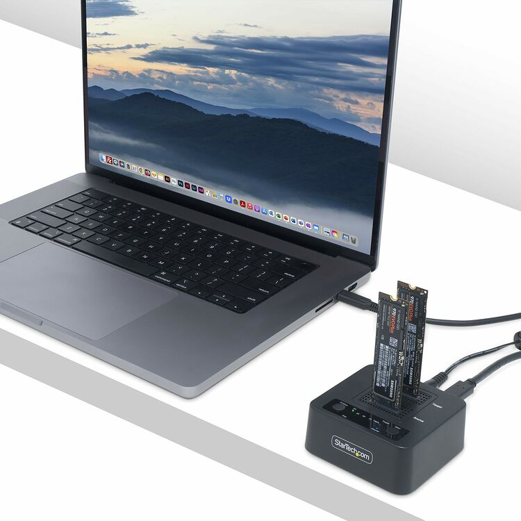 Un ordinateur portable gris relié à un hub StarTech.com sur lequel sont insérées deux barrettes de mémoire SSD NVMe.