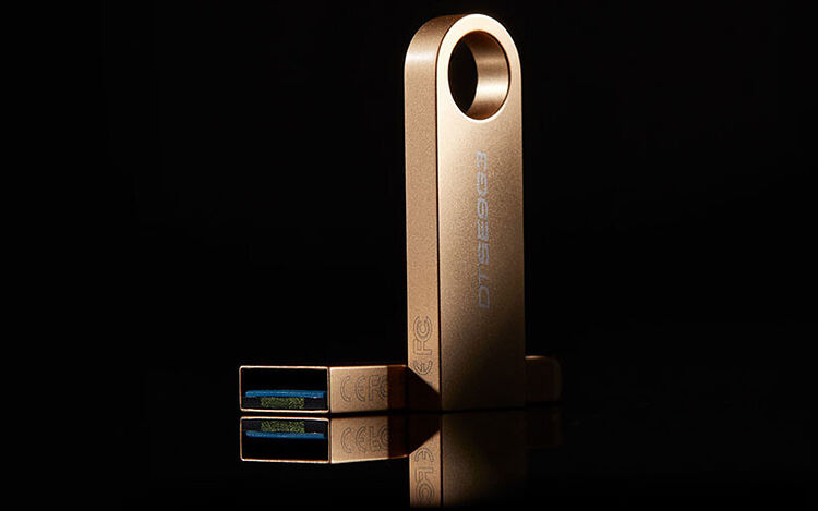 Une clé USB de couleur dorée avec un design allongé et une ouverture circulaire à l'extrémité.