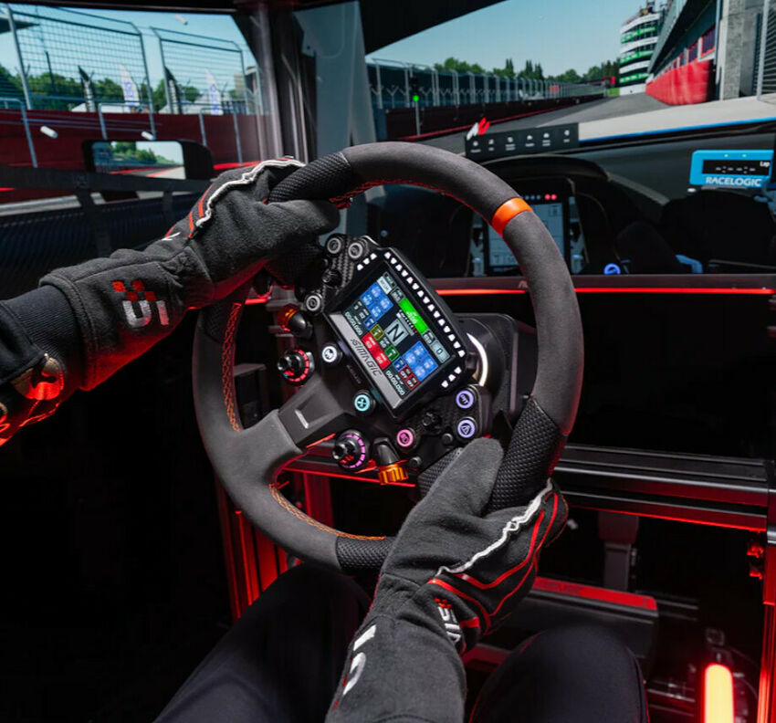 Une personne portant des gants de course tient un volant de simulation avec écran intégré.