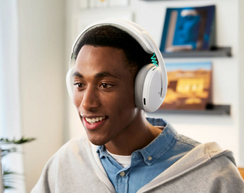 Un jeune homme souriant portant un casque audio blanc avec des détails vert menthe.