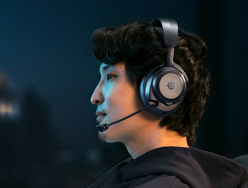 Un homme portant un casque audio de marque SteelSeries avec un micro intégré, sur un fond sombre.