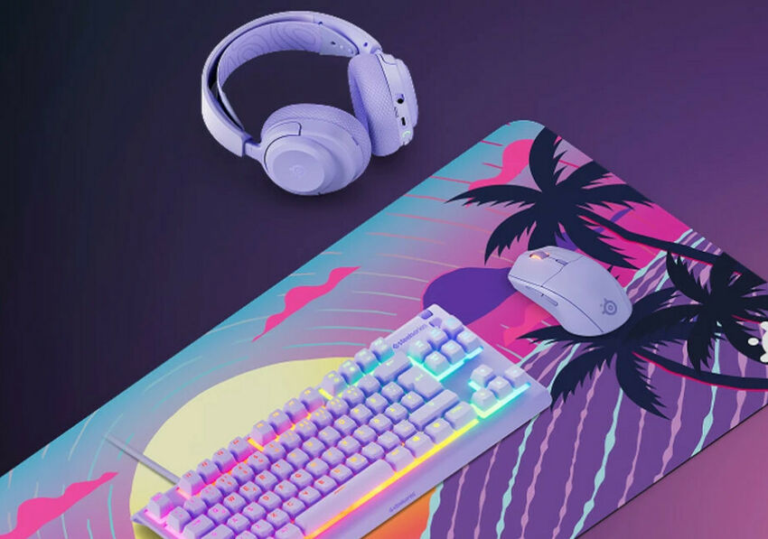 Un ensemble de périphériques gaming comprenant un clavier mécanique, une souris et un casque sans fil, tous de couleur blanche, posés sur un tapis de souris au motif de palmiers colorés.