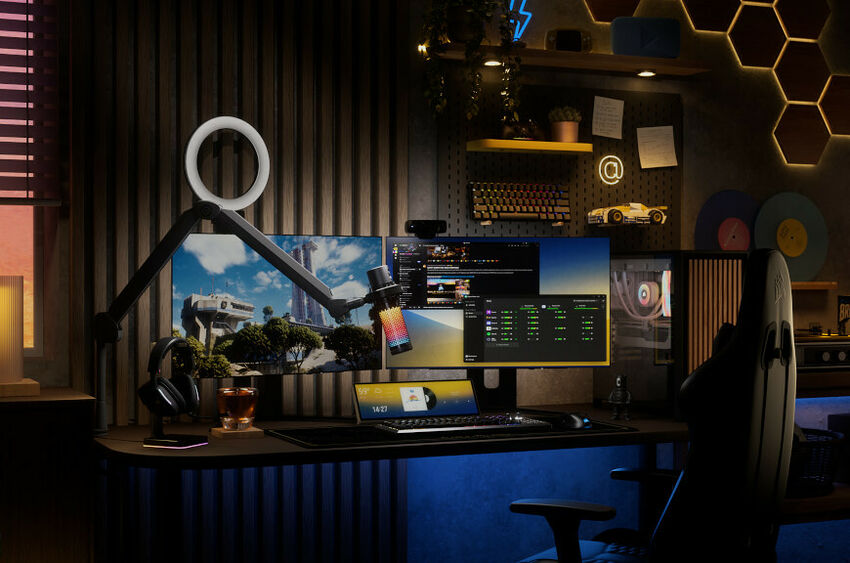 Un setup de bureau gaming avec deux écrans affichant des jeux et logiciels, un clavier, une souris, un casque audio et un anneau lumineux monté sur un bras articulé.
