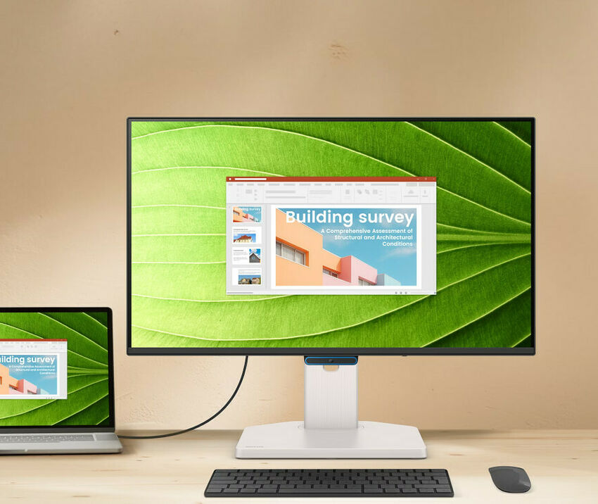 Un écran de bureau affichant une présentation sur l'inspection de bâtiments, accompagné d'un clavier noir et d'une souris sur un bureau en bois.