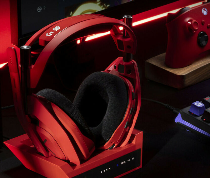 Casque gaming rouge Logitech posé sur son socle de recharge, avec une manette Xbox rouge en arrière-plan.