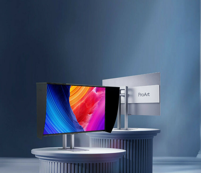 Écran de moniteur Asus ProArt avec un fond d'écran coloré, présenté sur un support blanc devant un panneau portant le logo ProArt.