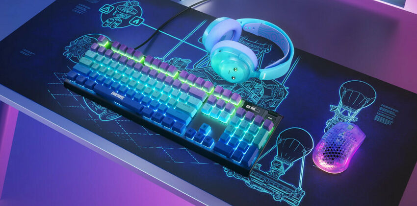 Un clavier mécanique rétroéclairé, un casque audio bleu clair et une souris gaming lumineuse posés sur un tapis de souris noir avec des motifs bleus.