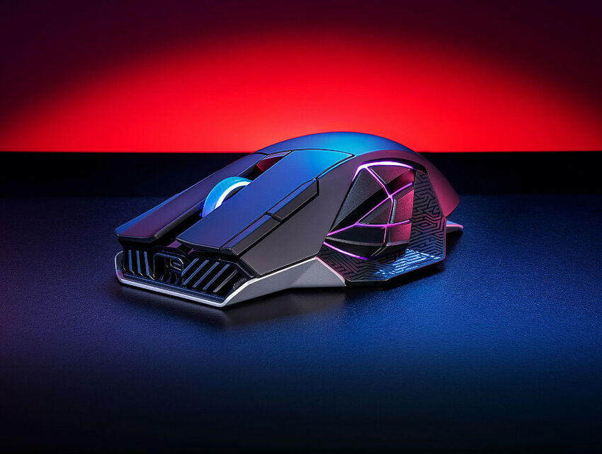 Souris gamer avec un design angulaire et un éclairage RGB intégré, posée sur une surface sombre avec un fond rouge et noir.