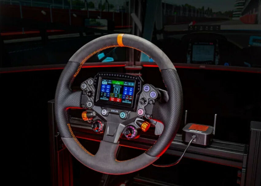 Volant de simulation de course Zeus avec écran digital central affichant des données de conduite, boutons de commande et revêtement en alcantara gris et noir avec surpiqûres orange.