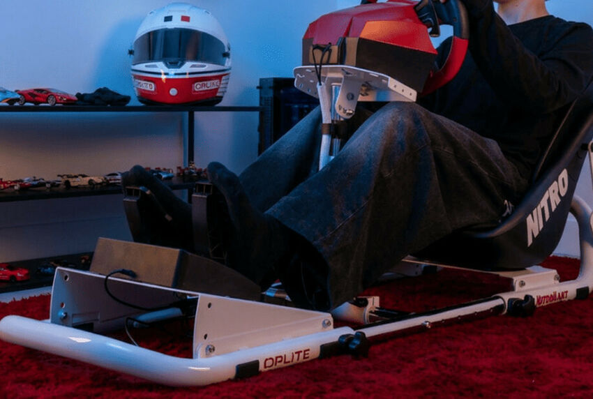 Un simulateur de conduite avec un siège de type baquet noir marqué Nitro, un volant de course rouge et noir, et une base de pédalier blanche de la marque OPLITE.
