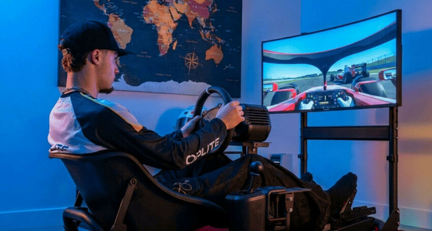 Un homme assis dans un cockpit de simulation de course avec un volant et un écran large affichant un jeu de course automobile.