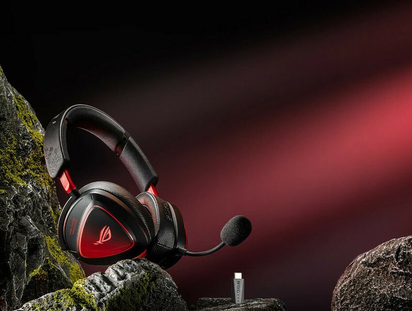 Casque gaming ASUS ROG noir et rouge avec micro déporté, posé sur des rochers sombres.