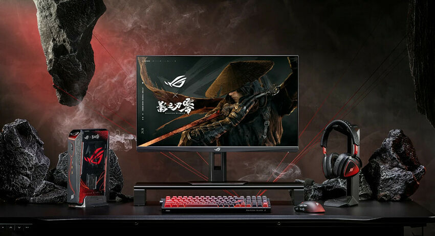 Un setup gaming comprenant un écran ASUS ROG, un clavier mécanique rétroéclairé rouge, une souris et un casque audio, le tout disposé sur un bureau noir entouré de rochers.