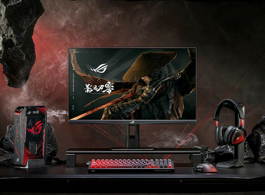 Un setup gaming comprenant un écran ASUS ROG, un PC fixe ASUS ROG, un clavier mécanique rétroéclairé, une souris et un casque gaming rouge et noir, le tout disposé sur un bureau noir.