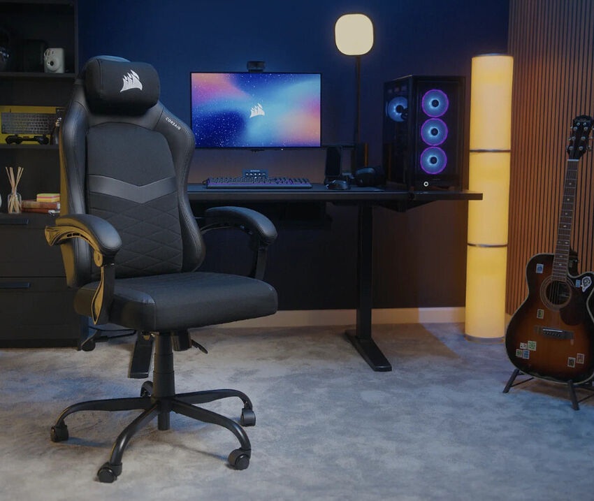 Un espace de travail gaming comprenant un siège Corsair noir, un bureau avec un PC équipé de ventilateurs lumineux, un écran et un clavier, le tout dans une pièce avec un éclairage d'ambiance et une guitare.