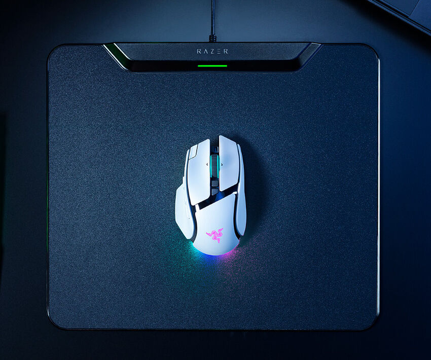 Une souris Razer blanche avec des éclairages RGB posée sur un tapis de souris Razer noir.